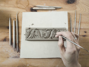 artist carving a ceramic tile from clay