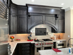 Modern kitchen with decorative black Victorian tiles, dark wood cabinets, stainless steel appliances, and white countertops.